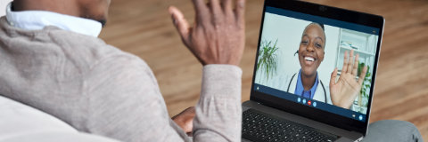 Person having a video call with a doctor on a laptop screen.