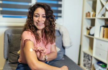Happy middle-aged woman pointing to a HTR patch on her arm